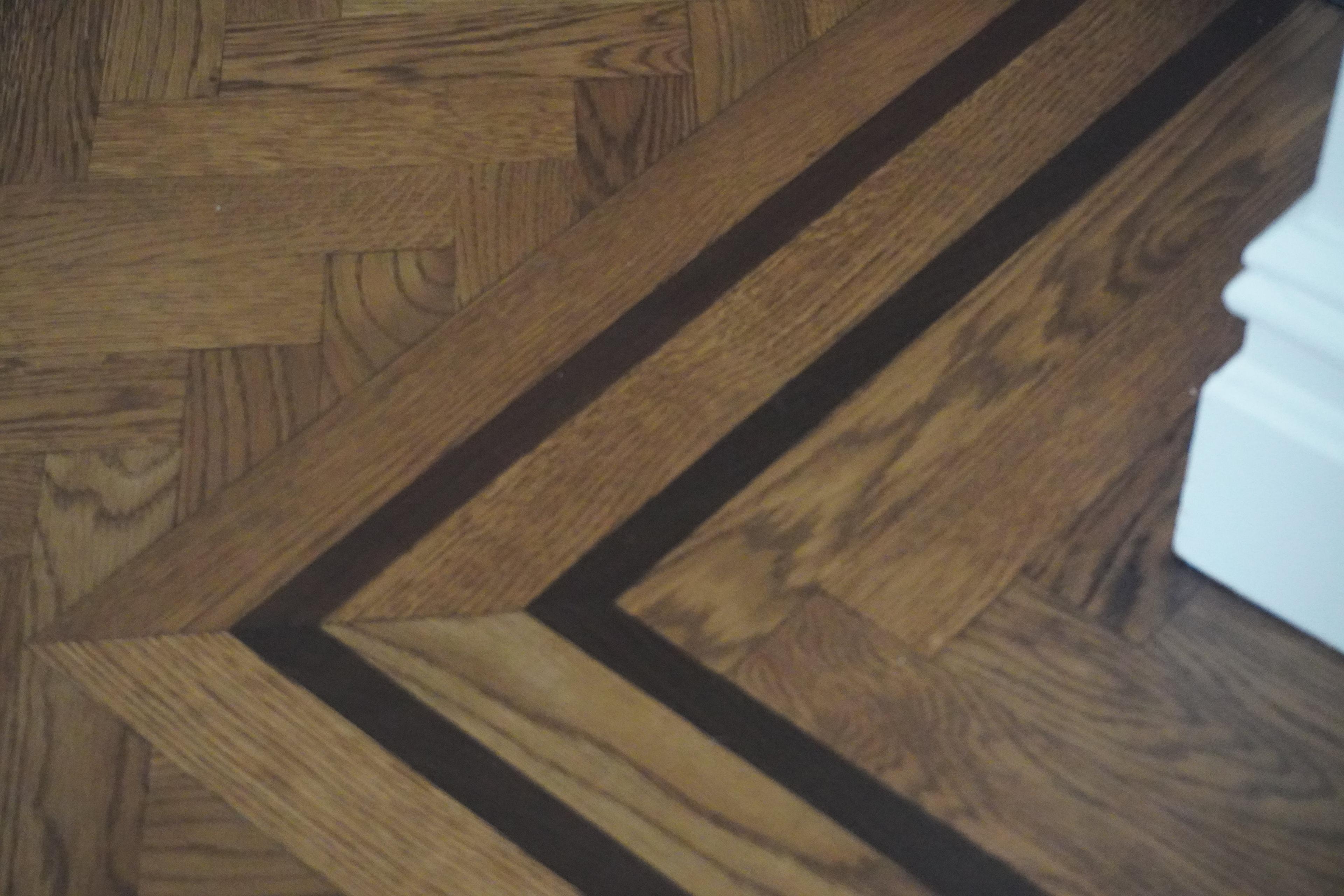 Herringbone hardwood meeting a bordered inlay at the corner of a room