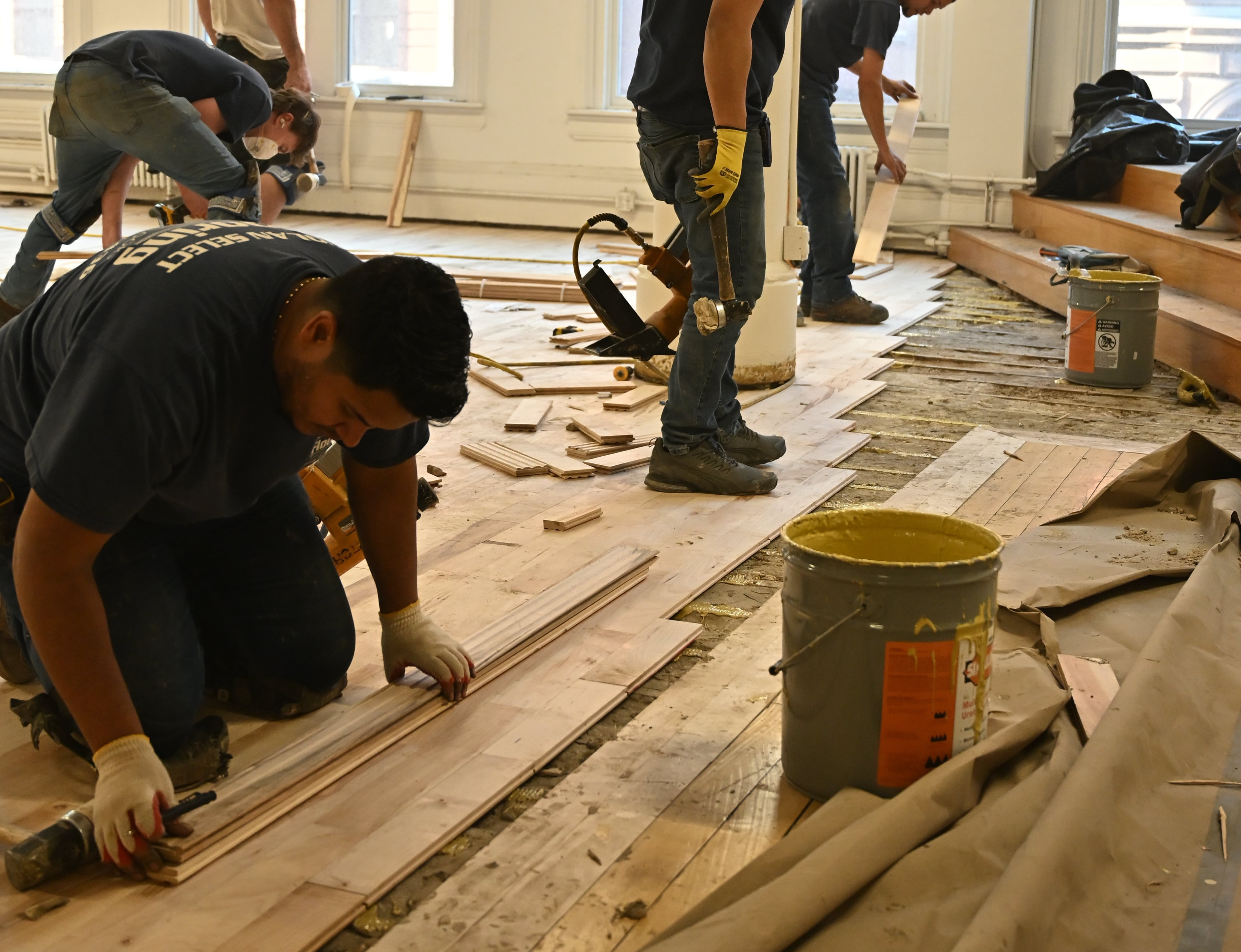 Nolan crew installing light hardwood planks over a subfloor